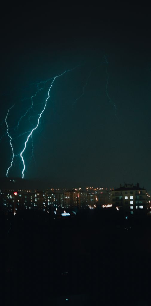 A striking night view of a cityscape illuminated by a powerful lightning bolt.