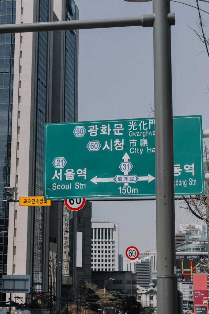 Traffic and directional signs in downtown Seoul with skyscrapers in the background.